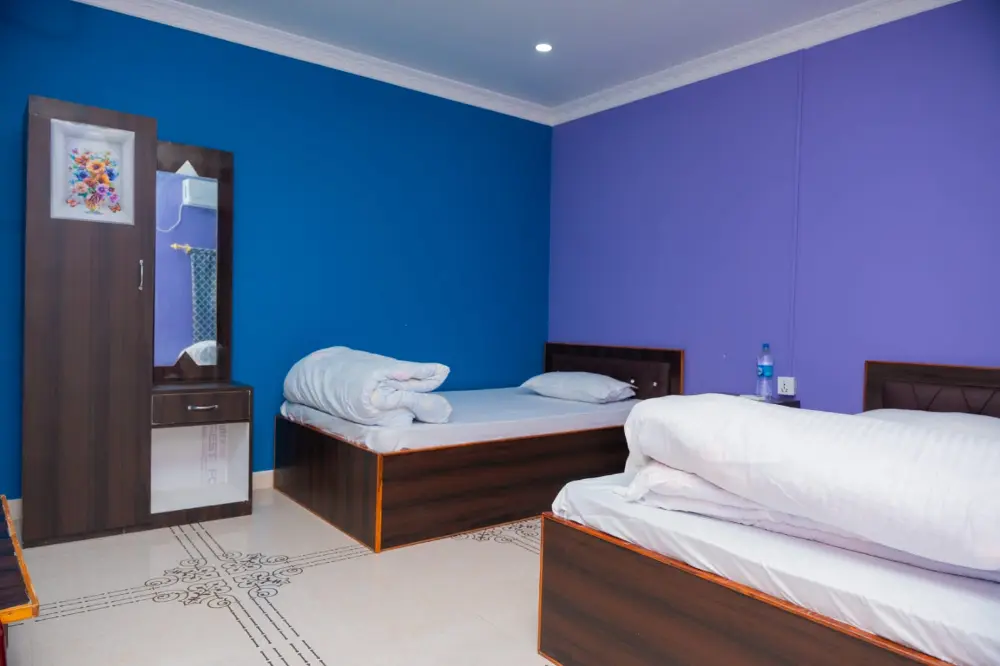 A guest room with two beds, a wardrobe and blue and violet walls